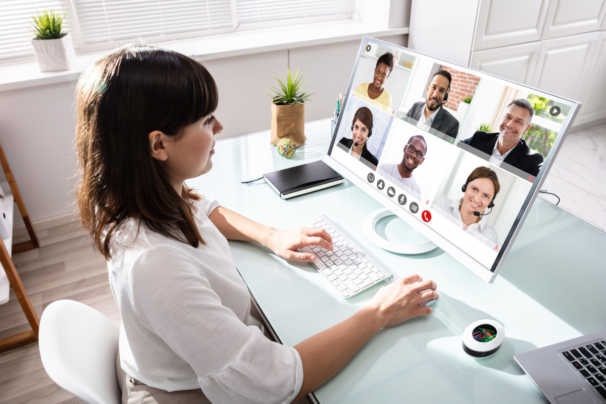 A woman using video conferencing software to speak with 4 colleagues